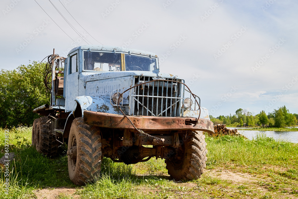 Dirty truck on a country green grass in a sunny summer day with blue sky.