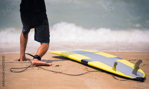 Canvas Print Fit surf instructor showing on the sunny beach how to stand on surfboard