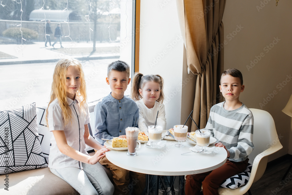 A large friendly company of children celebrate the holiday in a cafe with a delicious dessert. The day of the birth