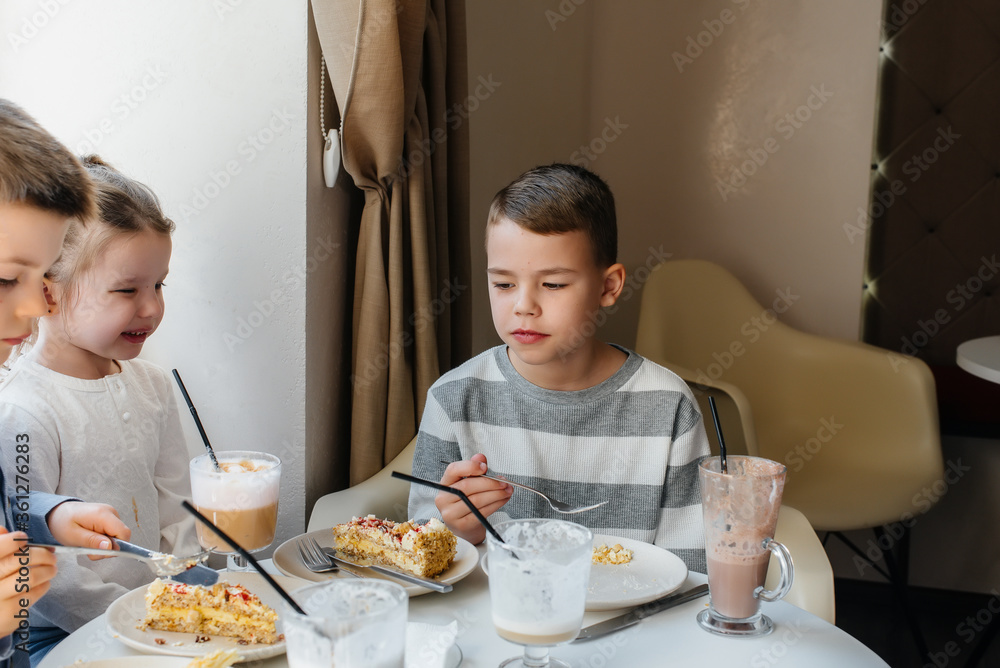 A large friendly company of children celebrate the holiday in a cafe with a delicious dessert. The day of the birth A large friendly company of children celebrate the holiday in a cafe with a delicious dessert. The day of the birth