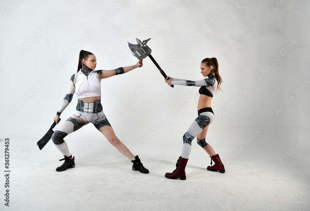 Obraz premium beautiful girls in costumes of robots quarreled and fight with a battle ax and a war hammer