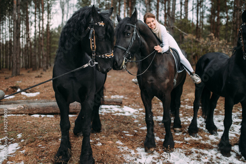 Picture of a beautiful young rider with three black horses