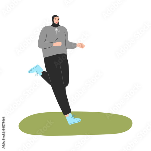 Young muslim woman in hijab and sport clothing jogging on grass
