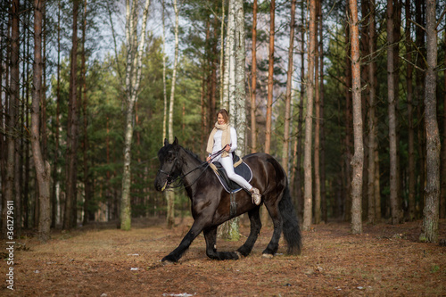 Beautiful girl with her Andalusian horse in the winter forest