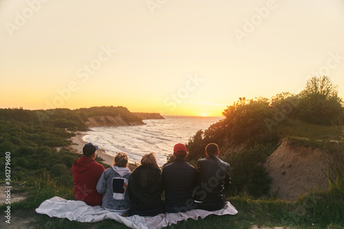 A group of friends watching the sunset at sea. View from the back. High-quality photo