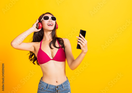 beautiful young woman wearing swimsuit bikini and watching smart phone