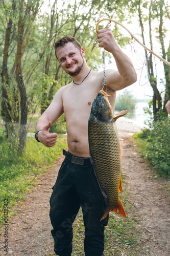 The fisherman holds in his hands a large fish caught. Good catch. Vertical photo, a hot summer day. photo