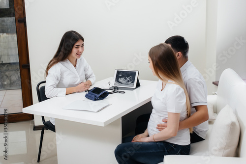 A young couple waiting for a baby to consult a gynecologist after an ultrasound. Pregnancy, and health care