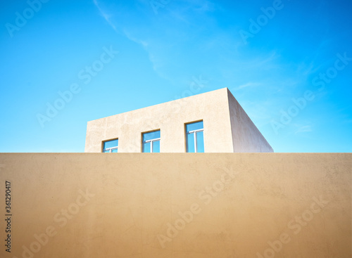 House with blue Windows behind a fence against the sky