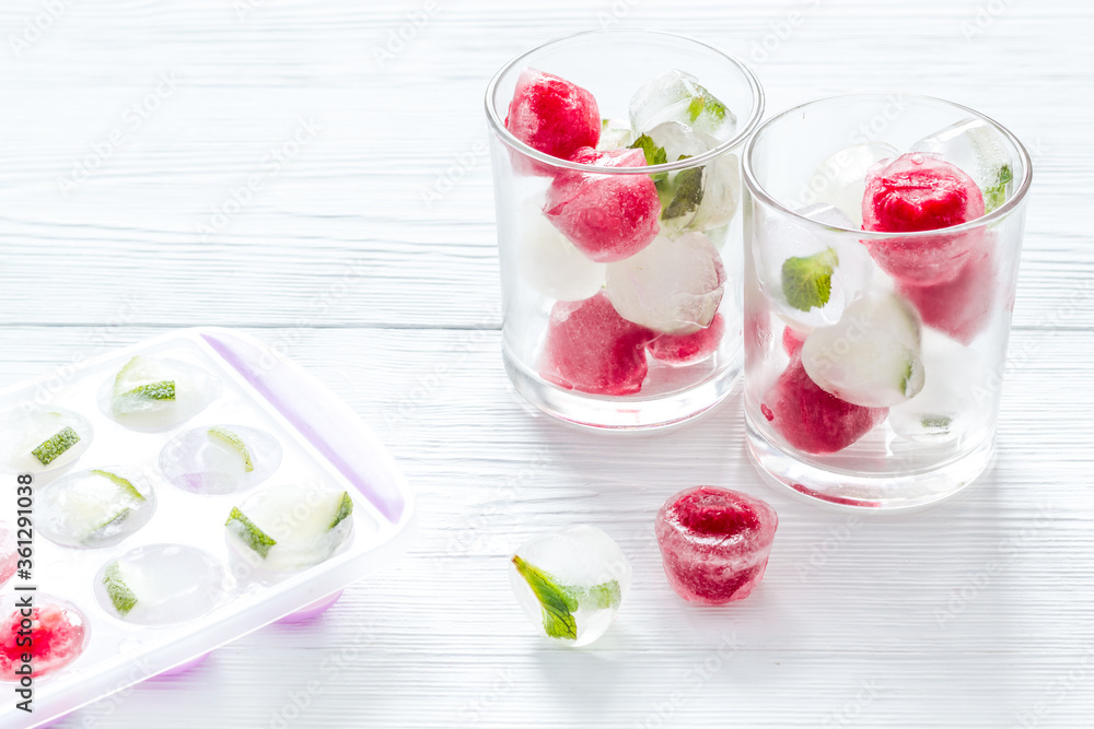 Cocktail glasses with berries in ice cubes on white table Cocktail glasses with berries in ice cubes on white table