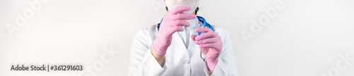 Cropped view of young female doctor in a white coat  in a medical mask and pink sterile gloves holding ampoule vaccines for children or older adults. Concept  diseases  medical care  diabetes.