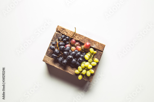 Wooden box with red grapes isolated on white background.