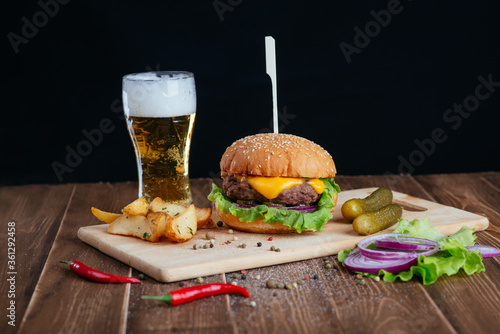 beer and snacks, hamburger and fries on a wooden board