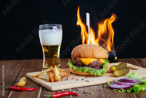 beer and snacks, hamburger with fries on a wooden board
