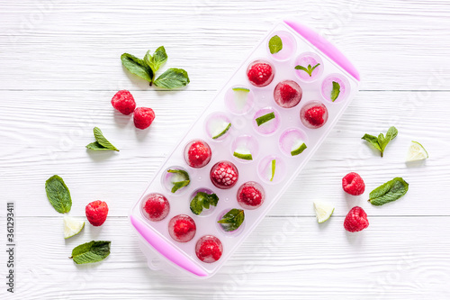 Ice tray with berries, lime and mint on white background top view