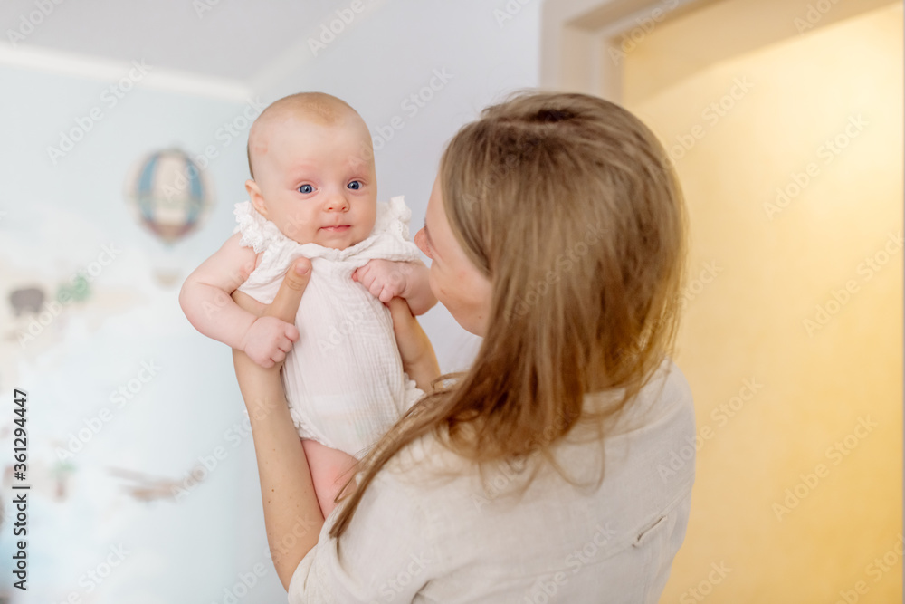 Beautiful young mother blonde in light clothes holds in her arms a newborn daughter 2 months Beautiful young mother blonde in light clothes holds in her arms a newborn daughter 2 months