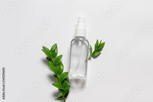 Natural homemade cosmetic plastic bottle with liquid and green leaves on grey background. Natural cosmetic products
