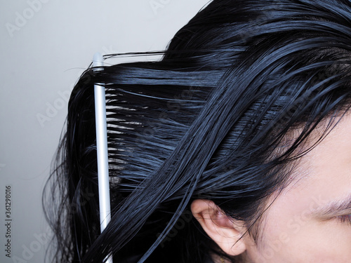 Close-up on head of Asian people have long black hair, combing hair with hairbrush. 
