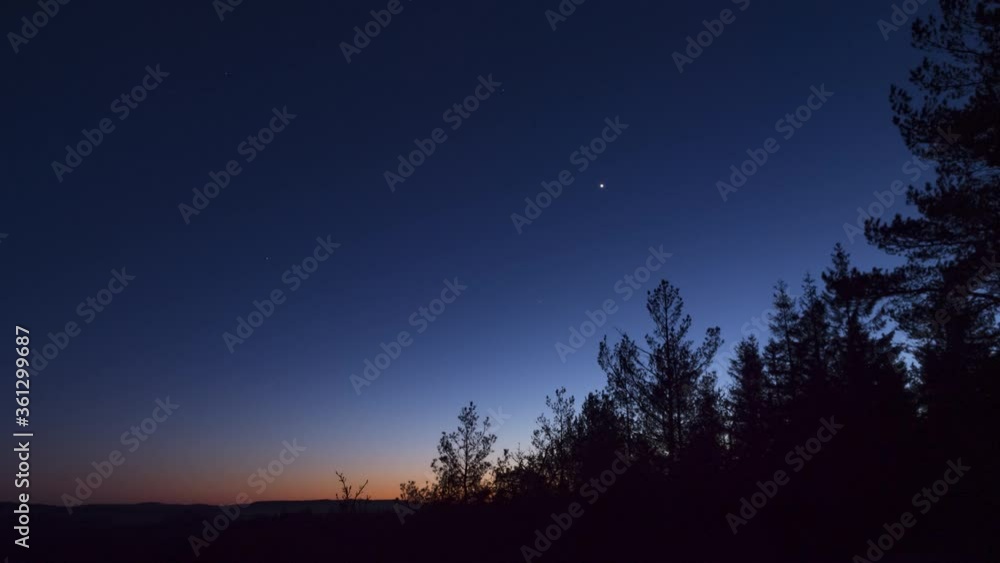 Time lapse sky darkens at nightfall over trees on clear sky evening Time lapse sky darkens at nightfall over trees on clear sky evening