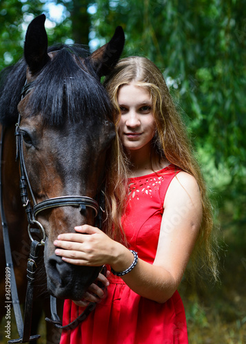 outdoor portrait of young beautiful woman with horse. Against the background of a tree