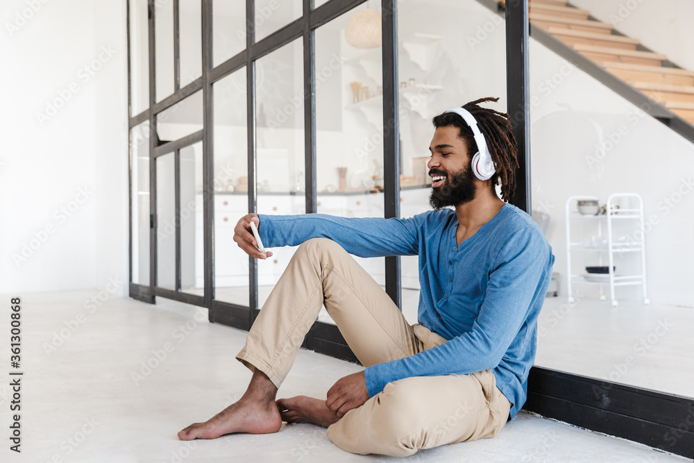 Cheerful young african man wearing wireless headphones Cheerful young african man wearing wireless headphones