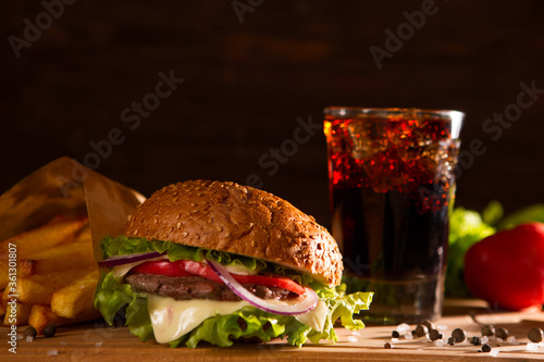 american snack with big burger and glass cola on wooden table