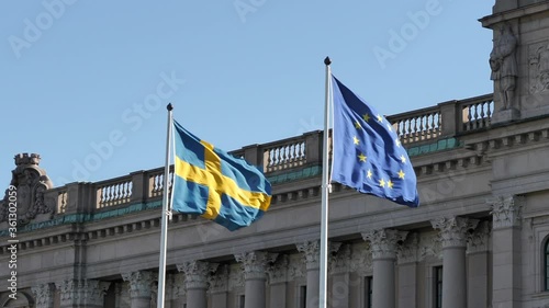 Swedish National and European Union Flags Waving on Wind in Front of Government Building photo