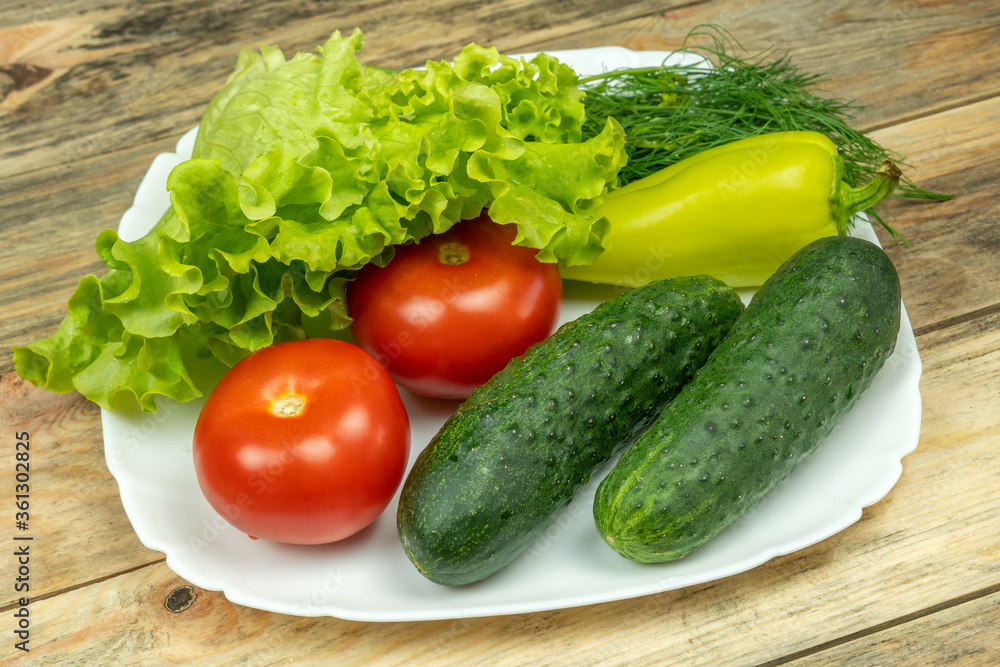 beautiful fresh, juicy vegetables on a white plate: fresh peppers, tomatoes, cucumbers, lettuce, dill beautiful fresh, juicy vegetables on a white plate: fresh peppers, tomatoes, cucumbers, lettuce, dill