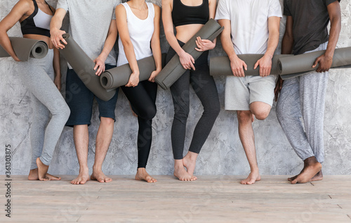Wellness Concept. Sporty People With Yoga Mats Standing Near Gray Wall