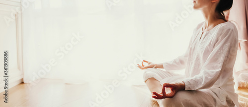 Woman practicing yoga lesson, breathing, meditating Lotus pose with mudra gesture