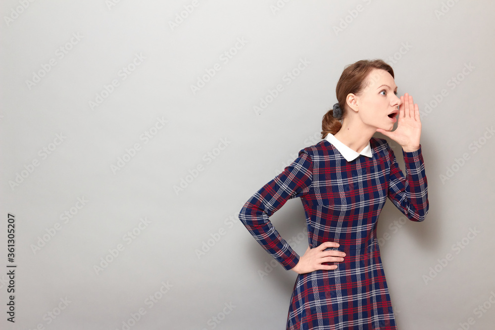 Portrait of amazed girl screaming loudly to side with hand near mouth Portrait of amazed girl screaming loudly to side with hand near mouth
