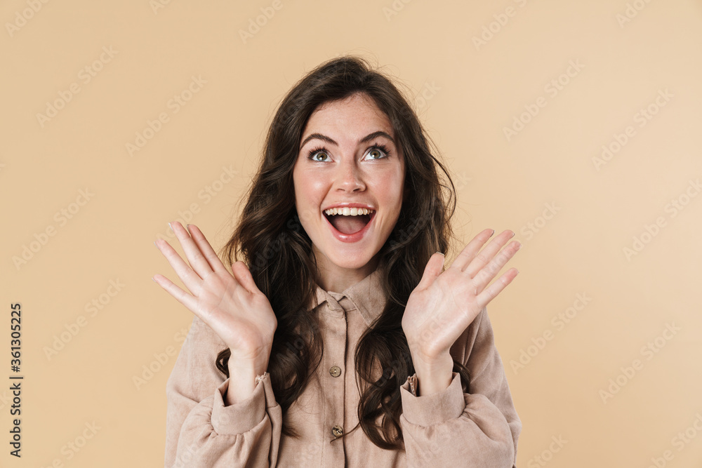 Image of delighted attractive woman expressing surprise on camera isolated over beige background Image of delighted attractive woman expressing surprise on camera isolated over beige background