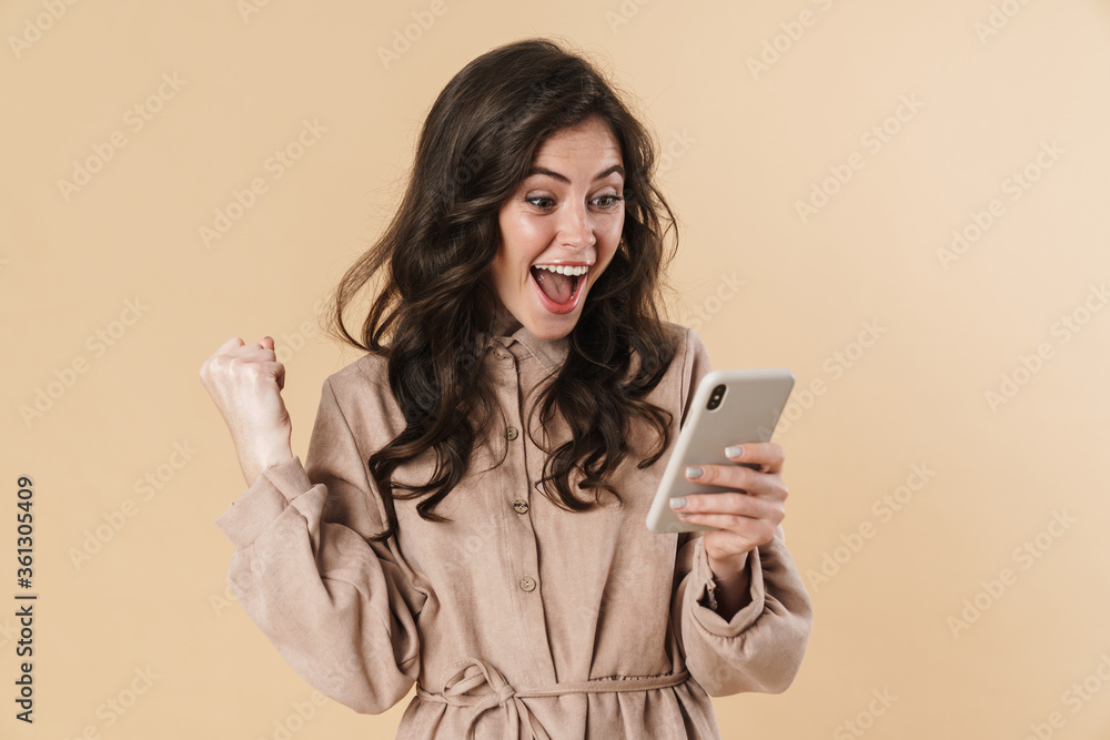 Image of cheerful woman making winner gesture and using mobile phone Image of cheerful woman making winner gesture and using mobile phone
