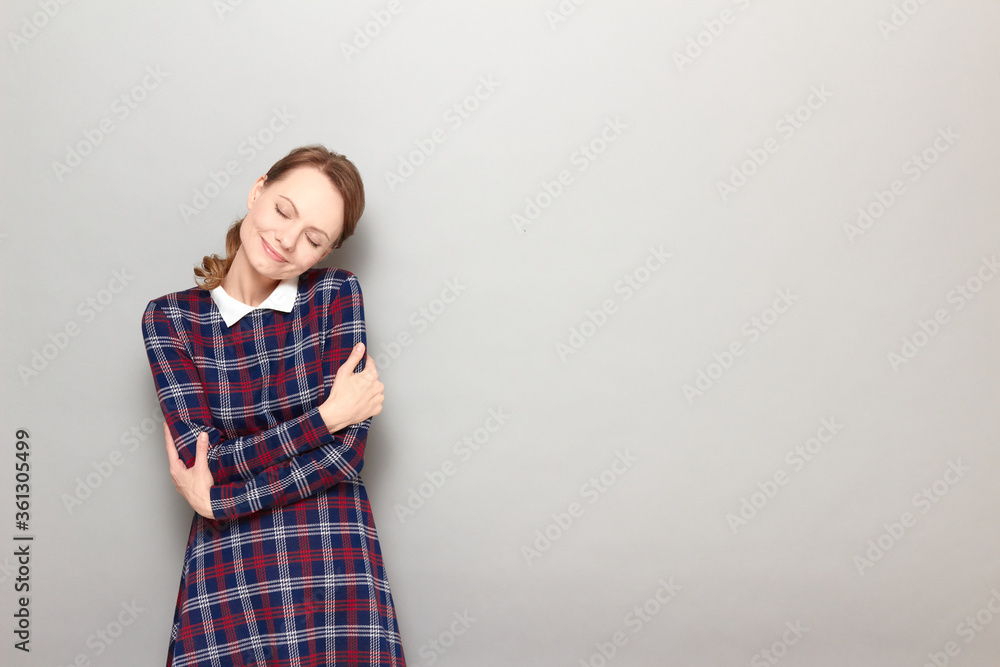 Portrait of happy girl hugging herself and smiling with closed eyes Portrait of happy girl hugging herself and smiling with closed eyes