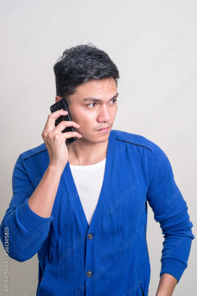 Portrait of young handsome Asian man talking on the phone Portrait of young handsome Asian man talking on the phone