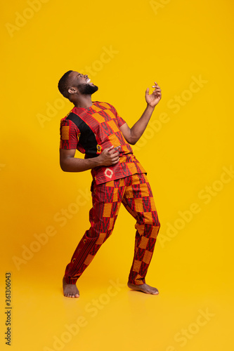 Joyful african man fooling over yellow background