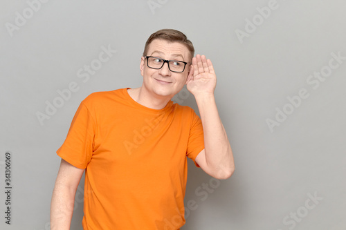 фотографія Cheerful man is placing hand near ear and eavesdropping conversation