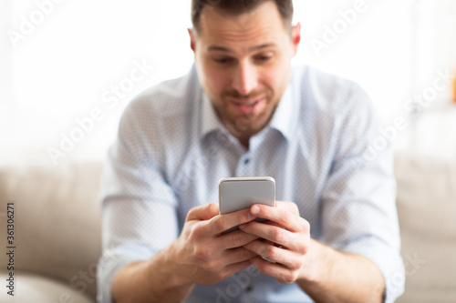 Handsome adult man using smart phone at home © Prostock-studio