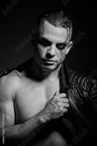 A man with embossed muscles and a naked torso in a leather jacket