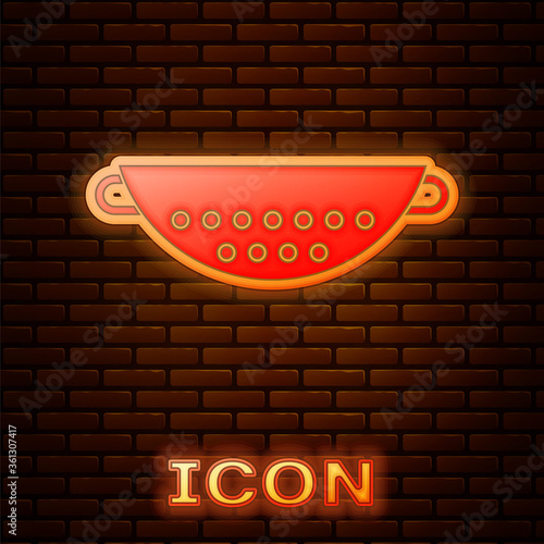 Glowing neon Kitchen colander icon isolated on brick wall background. Cooking utensil. Cutlery sign. Vector Illustration.