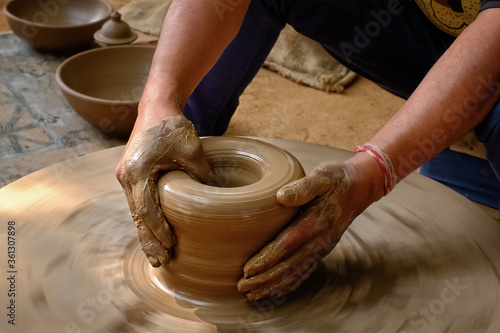 Pottery - skilled wet hands of potter shaping the clay on potter wheel. Pot, vase throwing. Manufacturing traditional handicraft Indian bowl, jar, pot, jug. Shilpagram, Udaipur, Rajasthan, India