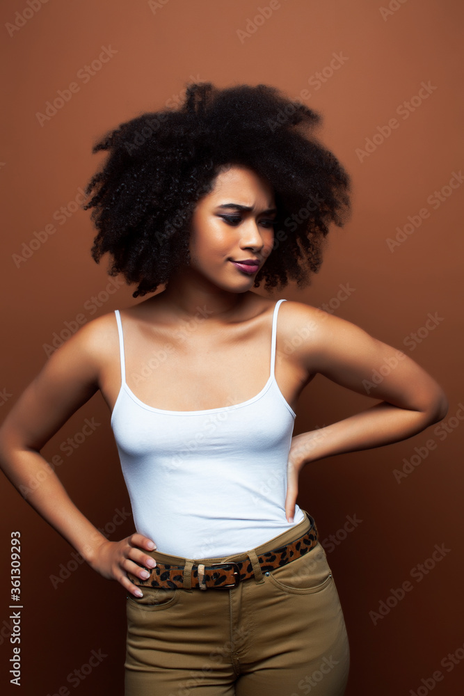 pretty young african american woman with curly hair posing cheerful gesturing on brown background, lifestyle people concept pretty young african american woman with curly hair posing cheerful gesturing on brown background, lifestyle people concept