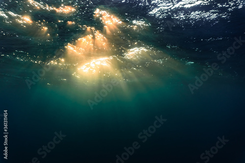 Rays of light shining through the surface of the atlantic ocean, into the deep, blue and dark abyss