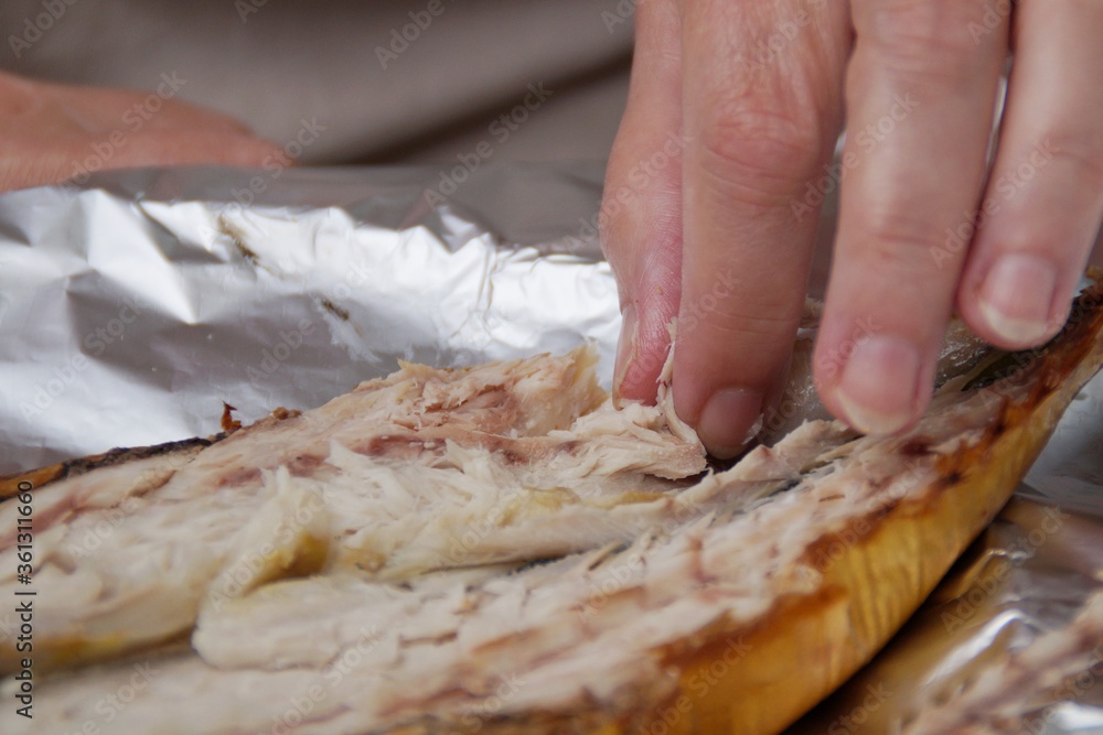 Hand of a woman eating smoked mackerel