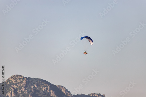 Tourists fly on motorcycle paragliders over mountains