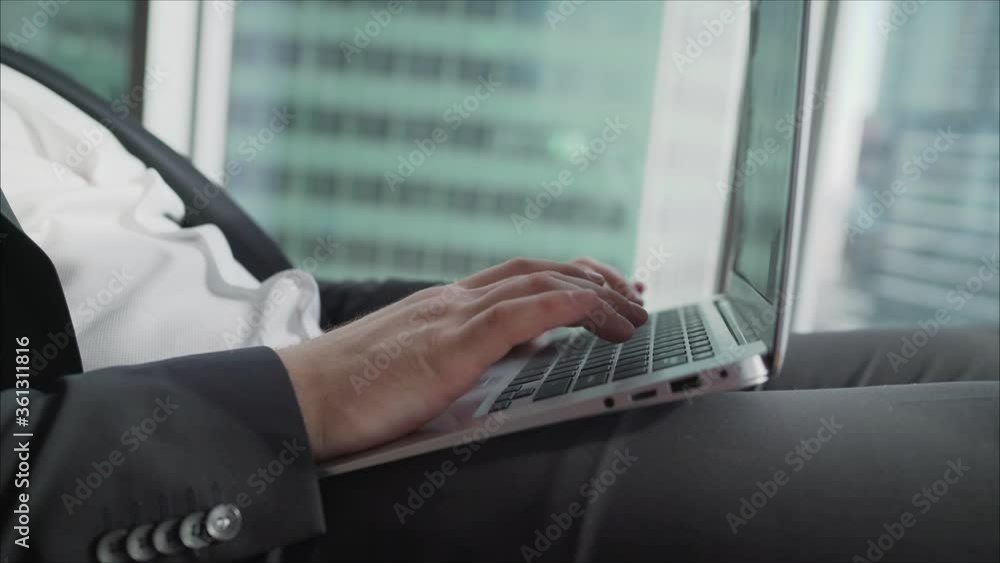 A businessman works behind a beech laptop in his office. Happy businessman wbrowsing web on his laptop in the office A businessman works behind a beech laptop in his office. Happy businessman wbrowsing web on his laptop in the office