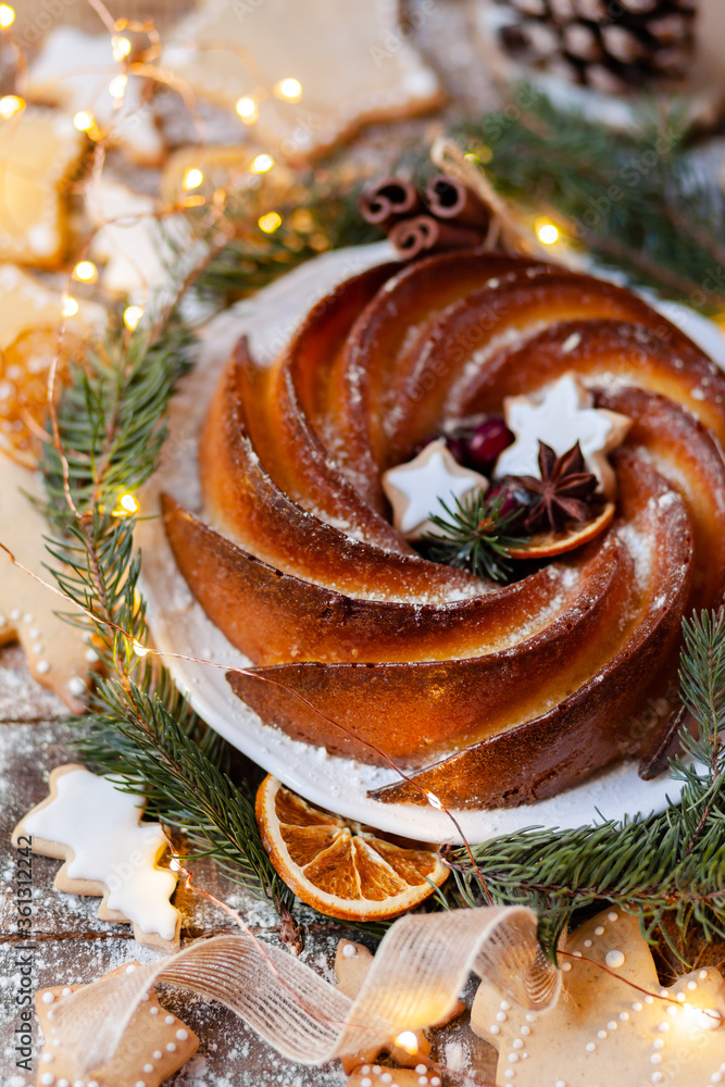 Delicious homemade freshly baked orange and lemon cake and gingerbread cookies. Rustic style decor, wooden background. Christmas festive holiday mood, cozy home atmosphere. Tasty traditional dessert