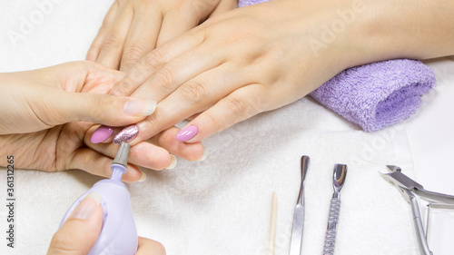 Manicure. Hardware manicure. Removal of old gel varnish in the salon. Manicure master doing beauty procedure for client. Manicurist is applying electric nail file drill to manicure on female fingers