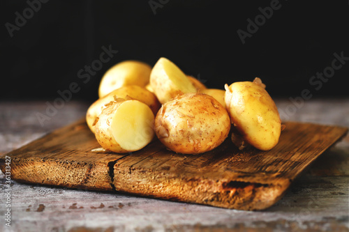 Selective focus. Young raw potato on a wooden surface. Fresh potato harvest.