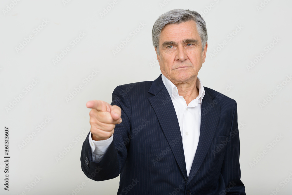 Portrait of handsome senior businessman in suit pointing finger Portrait of handsome senior businessman in suit pointing finger